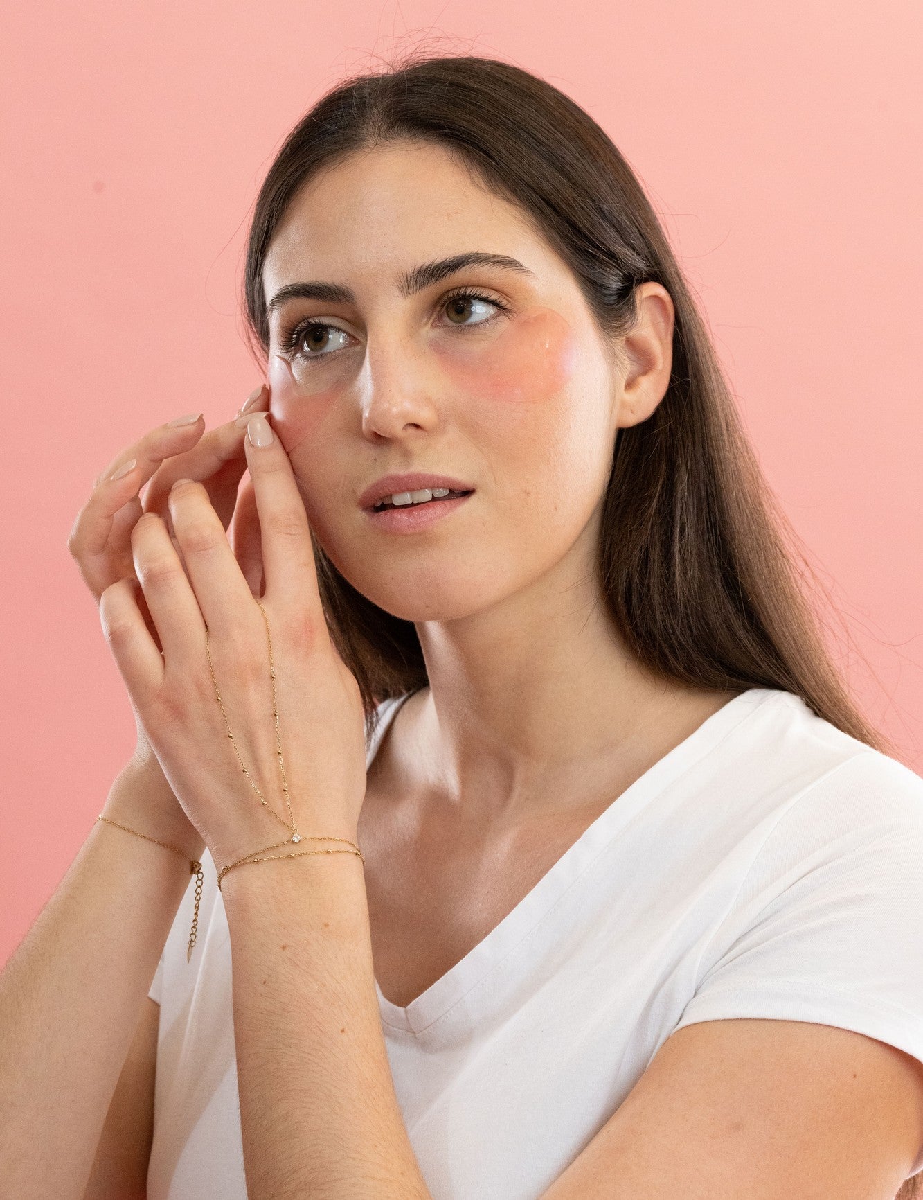 Femme brune ajustant les patchs anti-cernes Radieuse Paris sous ses yeux. Ces patchs hydrogel au Camélia Japonica hydratent, décongestionnent et réduisent les cernes et poches pour un regard éclatant et reposé.