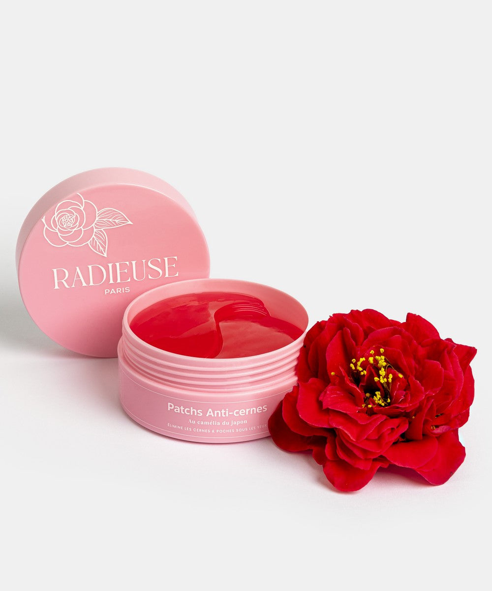 Pot rose de patchs anti-cernes Radieuse Paris ouvert, avec un patch rouge à l'intérieur, accompagné d'une fleur de camélia rouge. Patchs au Camélia Japonica, conçus pour réduire les cernes et poches sous les yeux, naturels, vegan et cruelty-free. Livraison offerte dès 40€ en France.