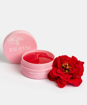 Pot rose de patchs anti-cernes Radieuse Paris ouvert, avec un patch rouge à l'intérieur, accompagné d'une fleur de camélia rouge. Patchs au Camélia Japonica, conçus pour réduire les cernes et poches sous les yeux, naturels, vegan et cruelty-free. Livraison offerte dès 40€ en France.