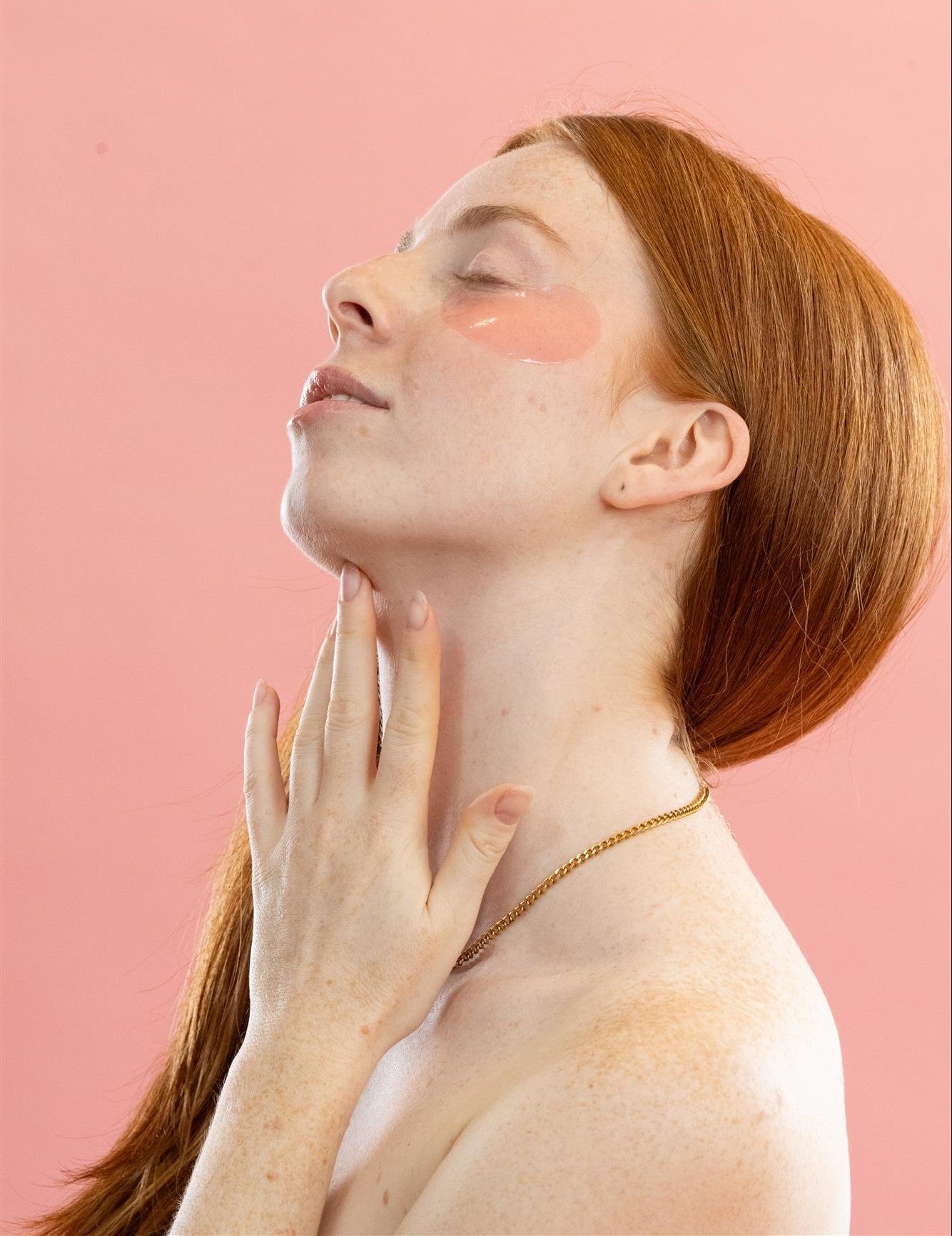Femme rousse profitant d’un moment de relaxation avec les patchs anti-cernes Radieuse Paris sous les yeux. Ces patchs hydrogel au Camélia Japonica hydratent, décongestionnent et réduisent les cernes pour un regard frais et reposé.