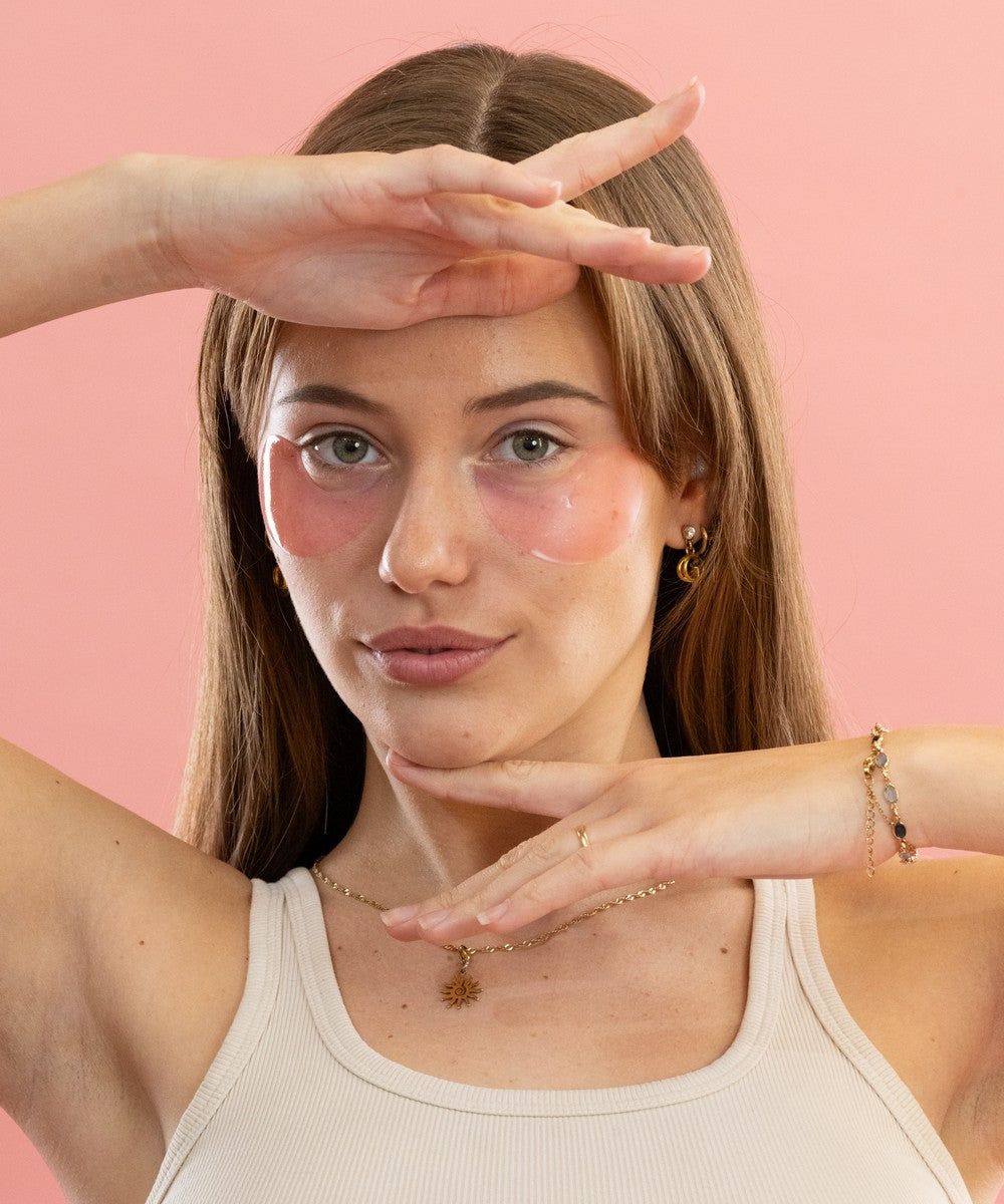 Femme portant des patchs anti-cernes Radieuse Paris et adoptant une pose artistique. Patchs naturels au Camélia Japonica, vegan et cruelty-free, conçus pour réduire les cernes et poches sous les yeux. Étape 1 : Nettoyez votre visage pour une absorption optimale. Étape 2 : Ajustez les patchs pour bien couvrir la zone des cernes. Étape 3 : Laissez poser 15 à 20 minutes pour des résultats optimaux. Étape 4 : Retirez et tapotez doucement pour faire pénétrer les actifs, sans rinçage. Produit évalué 100% sur YUKA