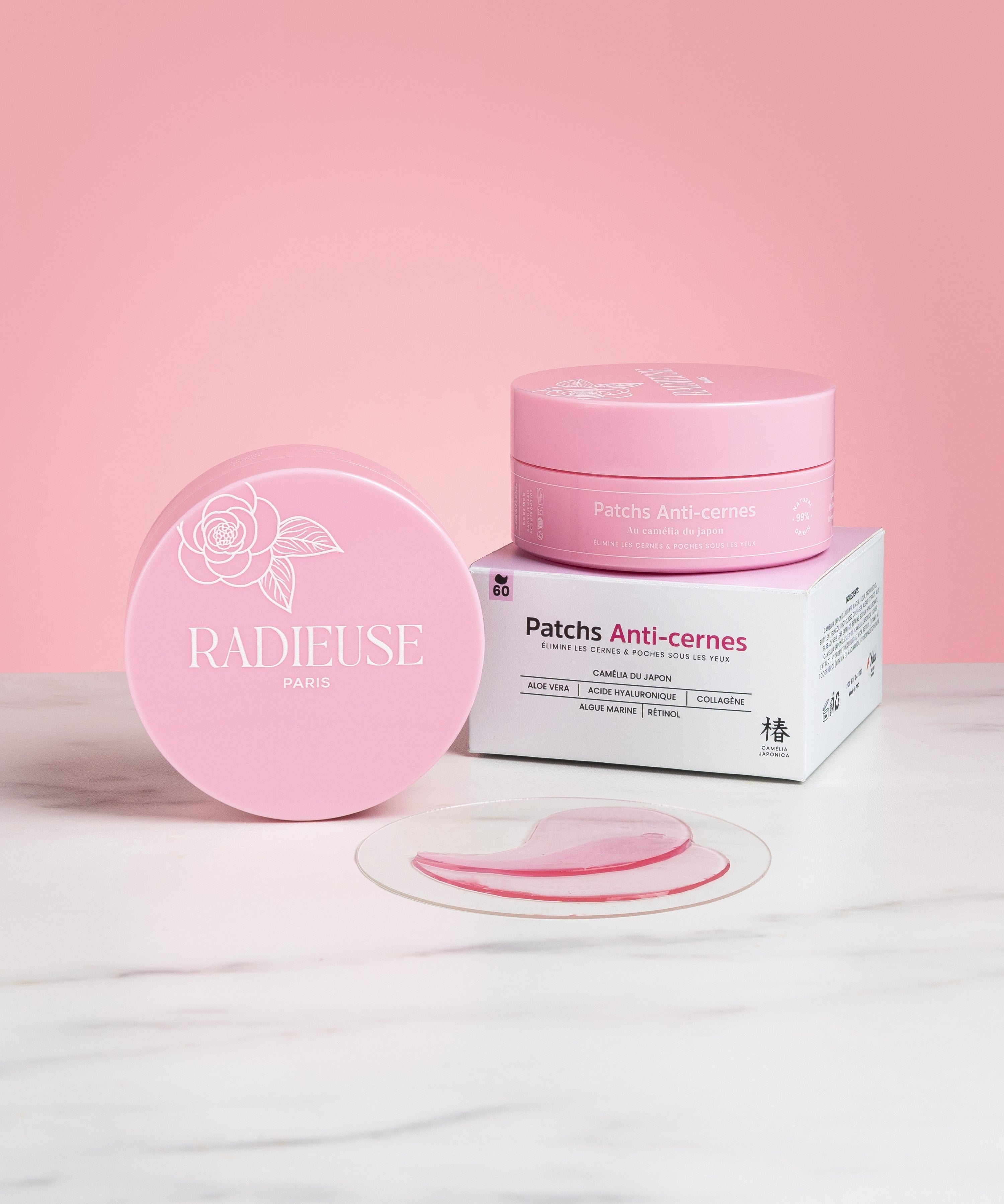 Boîte et packaging des patchs anti-cernes Radieuse Paris, avec une paire de patchs hydrogel disposée sur une surface en marbre. Enrichis en Camélia Japonica, aloe vera, acide hyaluronique et collagène, ces patchs hydratants et décongestionnants réduisent efficacement les cernes et poches.